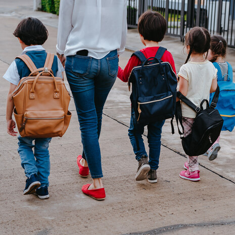 Mutter und vier Kinder mit Schultaschen 