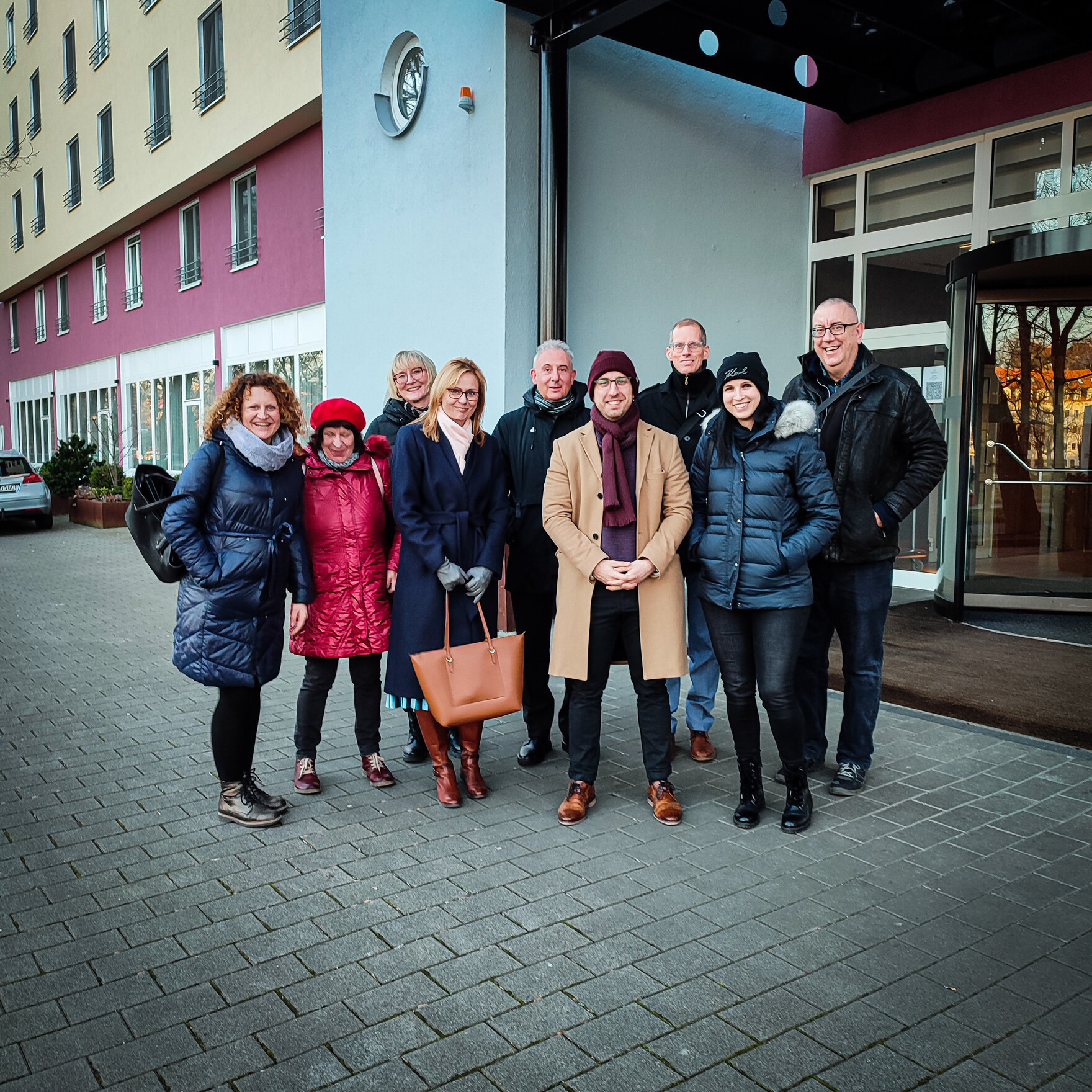 Eine Gruppe von Frauen und Männern stehen gemeinsam vor einem Gebäude