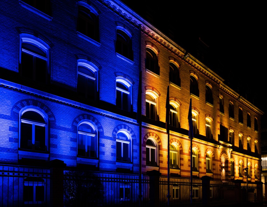 das Gebäude des SMJusDEG gelb und blau beleuchtet