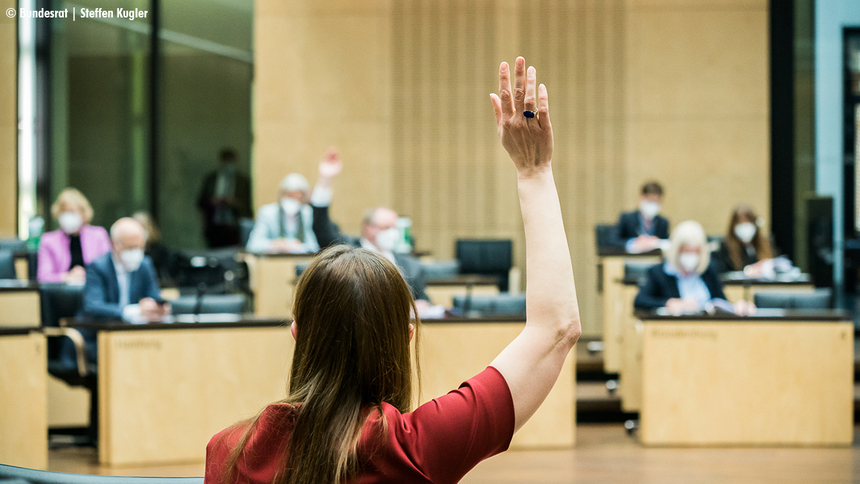 Ministerin Katja Meier von hinten fotografiert hebt die Hand im Bundesrat