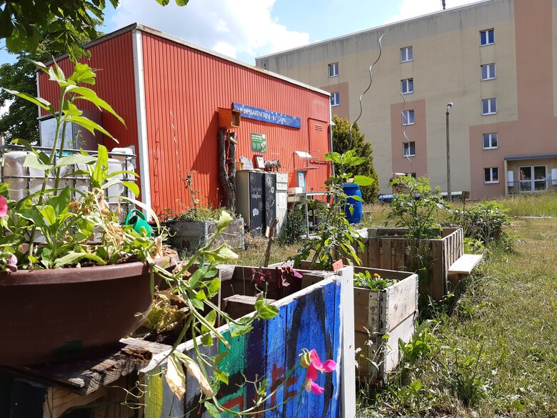 Ein Roter Wohnwagen in einem grünen Garten.