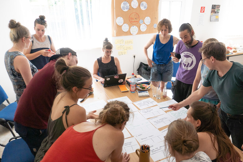 Menschen stehen um einen Tisch und diskutieren